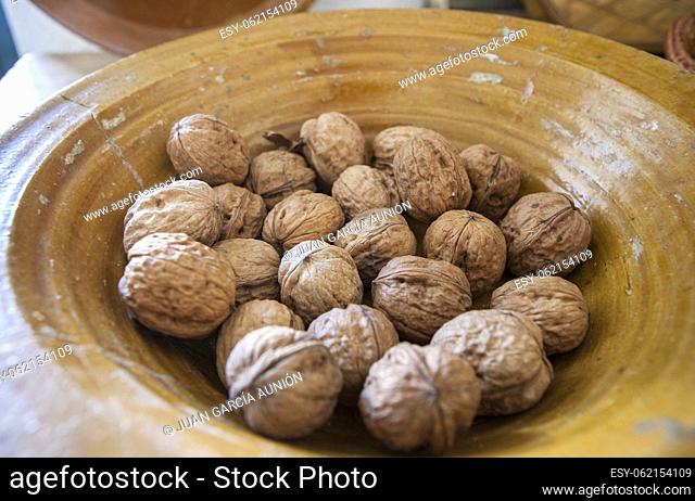 Glazed clay platter full of walnuts. Selective focus