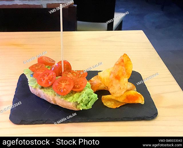 Tapa made of avocado and cherry tomatoes on toast with chips. Spain