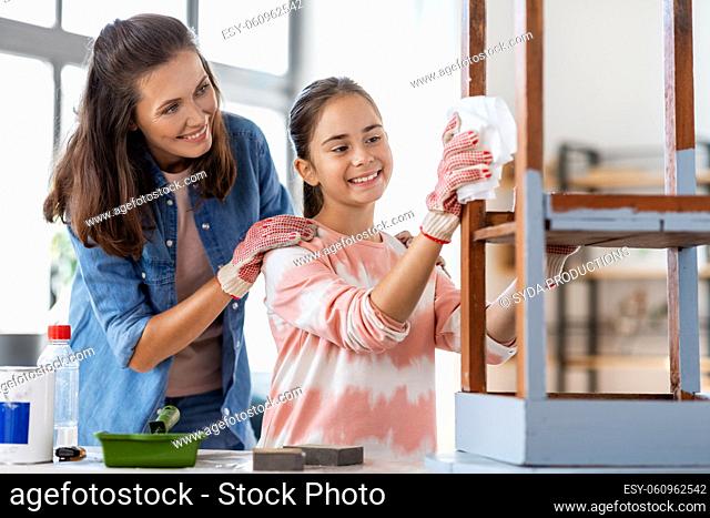 mother and daughter cleaning old table with tissue
