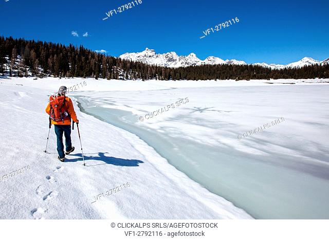 A hiker walking on the banks of Lake Palu now melting, Valmalenco, Valtellina, Italy