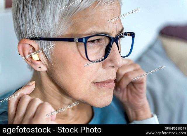 Mature woman using earplugs for sleeping