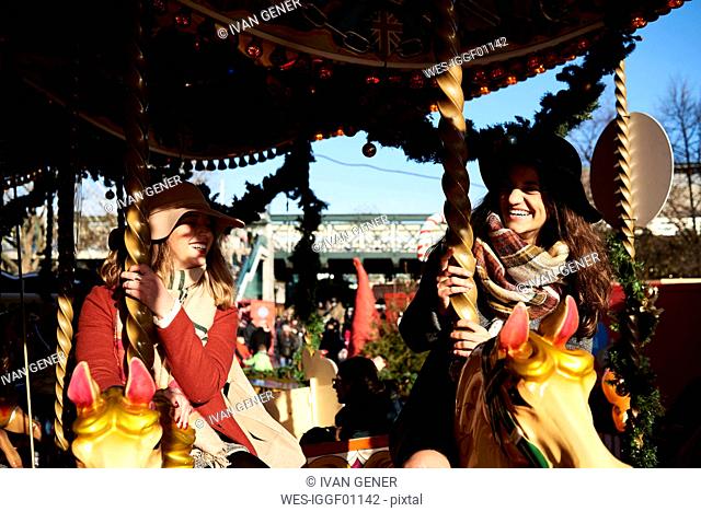 Two happy women having fun on a carousel