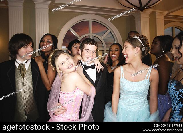 Teenagers smiling for the camera at formal dance
