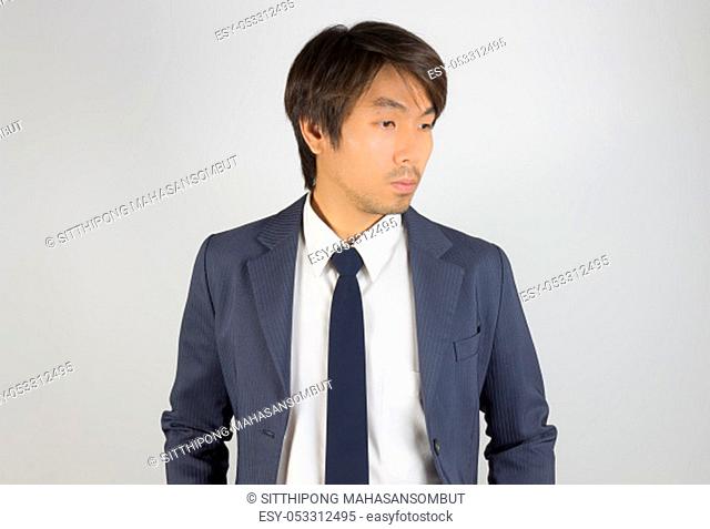 Young Asian Portrait Businessman in Navy Blue Suit Looking Below on Grey Background