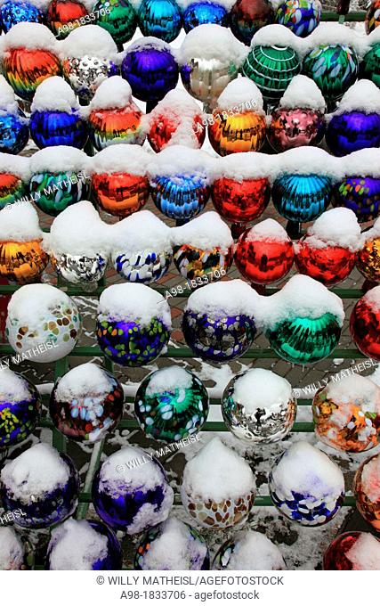 collection of colored glass balls decoration in garden in winter with snow