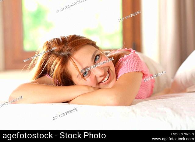 Portrait of a beautiful happy woman looking at camera lying on the bed at home