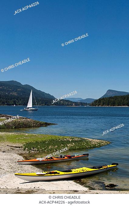 Kayaks and sailboat on Russell Island with view to Fulford Harbour, Saltspring Island, British Columbia, Canada