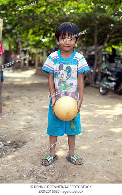 Portrait of a young boy with a ball in a small village outside of Phnom Penh, Cambodia