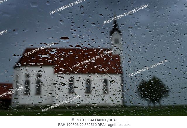 06 August 2019, Bavaria, Aitrang: The pilgrimage church Sankt Alban can be seen behind a rain-wet window. Photo: Karl-Josef Hildenbrand/dpa
