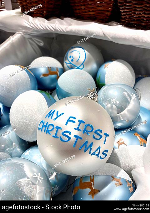 Cherished Debut: A 'My First Christmas' bauble gleams amid a sea of enchanting blue holiday ornaments, capturing the essence of festive beginnings