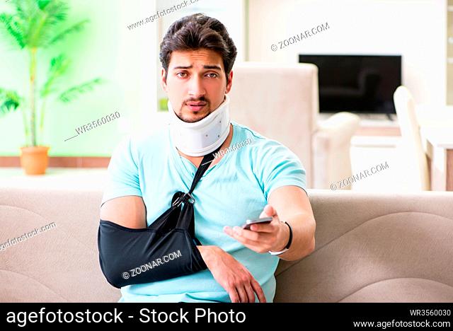 Young student man with neck and hand injury sitting on the sofa