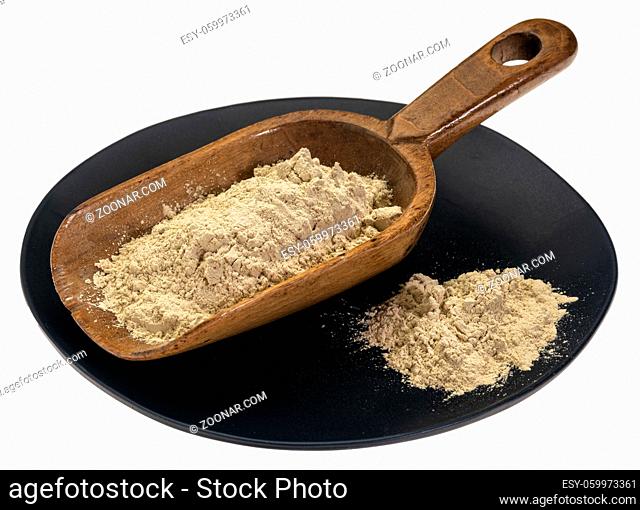 ashwagandha root (aka Indian ginseng) powder on rustic wooden scoop against isolated black plate