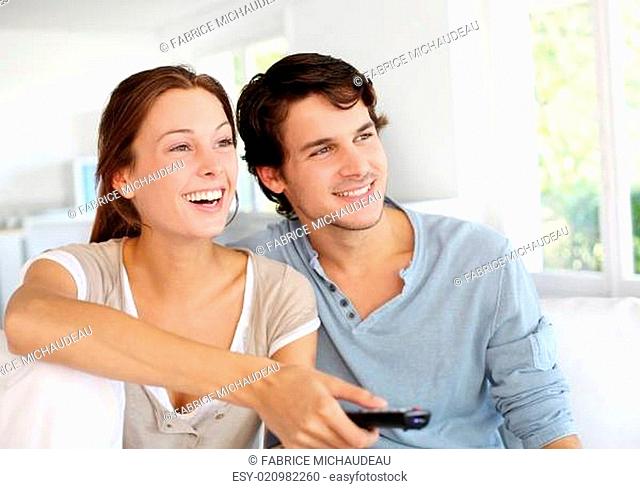Couple sitting in sofa with remote control in hands