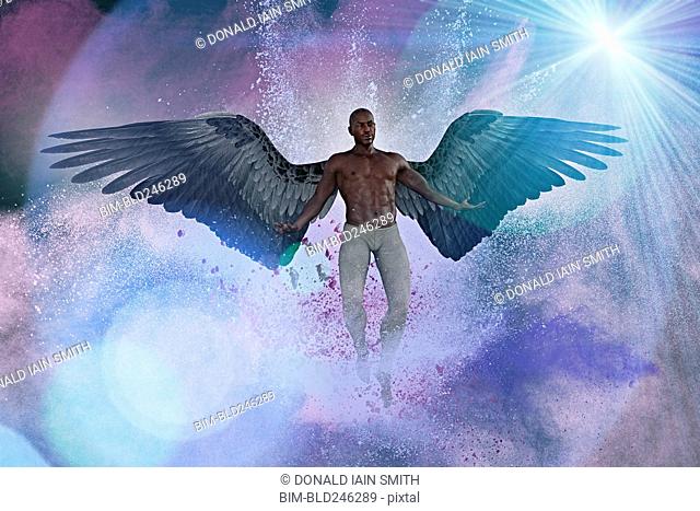 Man with angel wings flying in purple sky