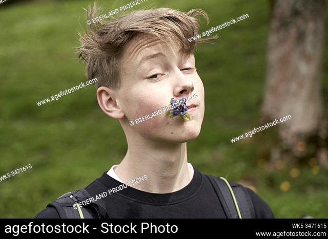 Young boy in countryside with flower in mouth. Bad Tölz, Upper bavaria, Germany