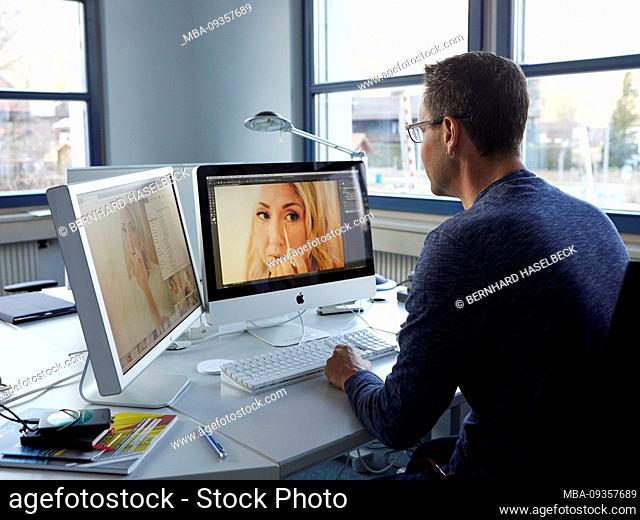 man sitting at desk in office doing image retouching