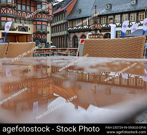 29 July 2023, Saxony-Anhalt, Wernigerode: Rainwater collects on a table on the market square in Wernigerode. The weather in the Harz Mountains is currently...