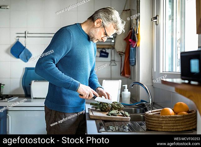 Mature man preparing artichokes in his kitchen