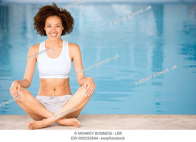 Woman sitting poolside smiling