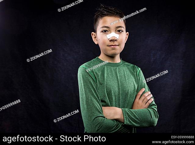 A close up portraiture of a confident athletic boy who has tape on his nose