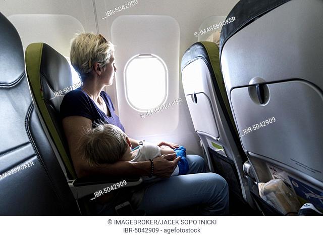 Mother with sleeping baby in a passenger airplane, Poland, Europe