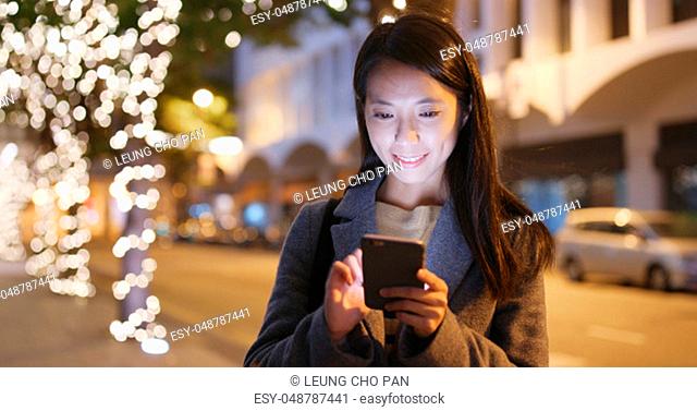 Businesswoman use of mobile phone in city at night