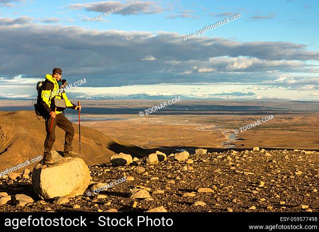 Man enjoying beautiful landscape panorama view with snowy mountains, river and desert in the icelandic highland