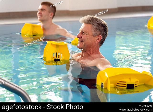 People in pool during water gymnastics physiotherapy doing exercises