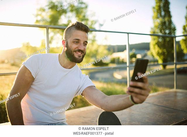 Smiling skateboarder taking selfie