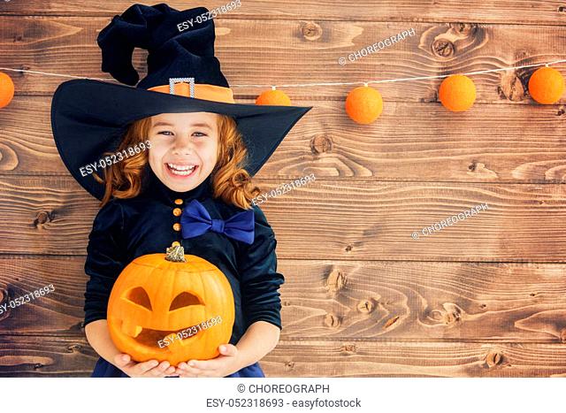 Happy Halloween! Cute little witch with a pumpkin