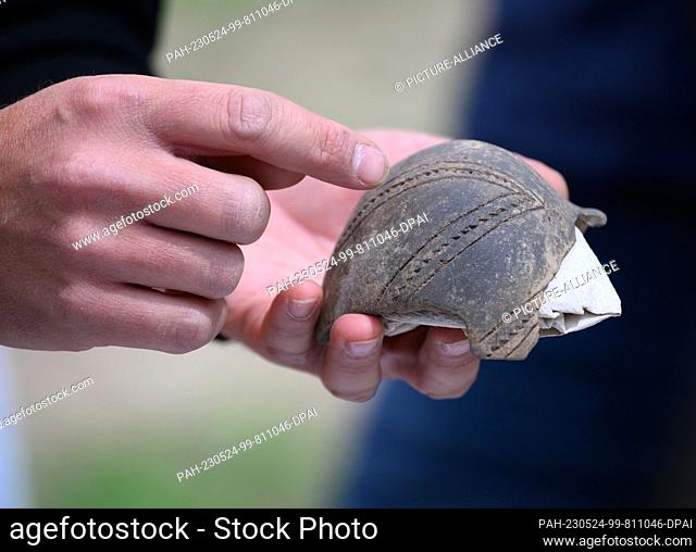 24 May 2023, Saxony, Döbeln: An employee of the Saxony State Office for Archaeology holds a part of a bottle from the Linear Pottery (ca