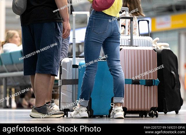 27 July 2022, Saxony, Dresden: Airline passengers stand next to their luggage at Dresden Airport. Due to the Verdi warning strike