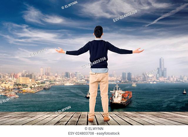 Asian man open arms and looking the skyline of the city, Kaohsiung, Taiwan, Asia