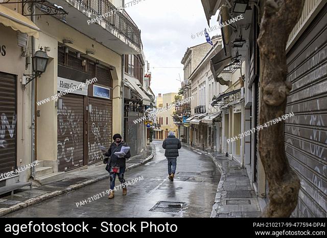 17 February 2021, Greece, Athen: A postwoman walks past closed shops in the Plaka district. A strict lockdown has been in effect for the greater Athens area for...