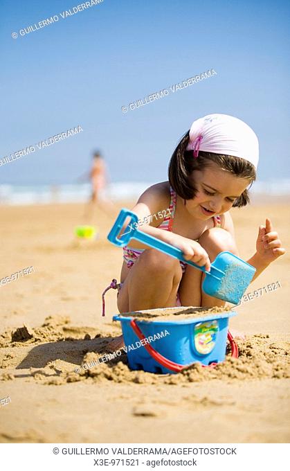 Niña jugando con la arena en la playa