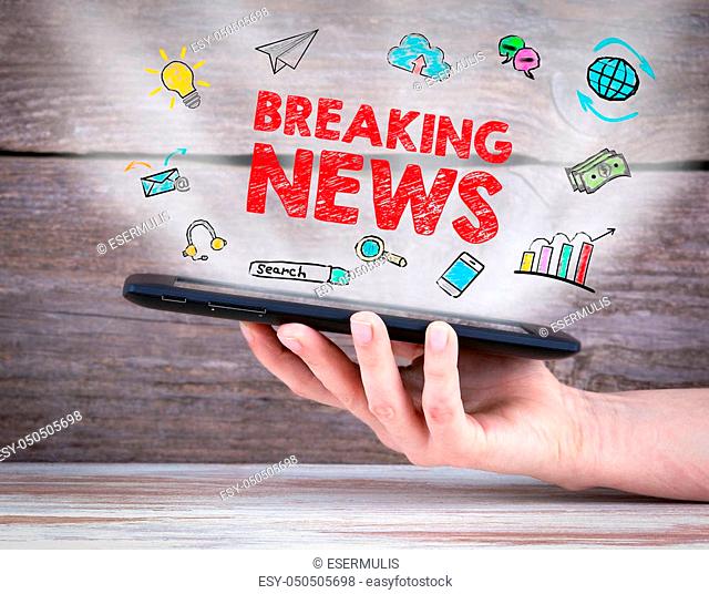 Breaking News. Tablet computer in the hand. Old wooden background