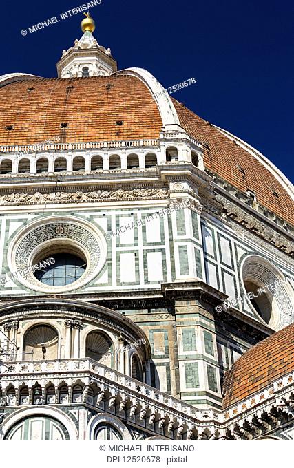 Close-up of Brunelleschi's Dome of Florence Cathedral decorative details of facade and blue sky; Florence, Tuscany, Italy