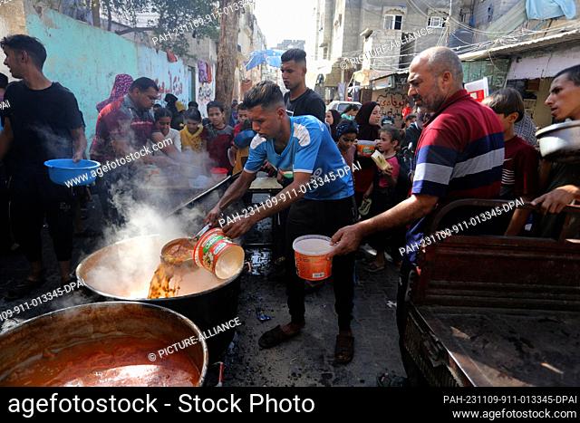 09 November 2023, Palestinian Territories, Rafah: Palestinian volunteers prepare and distribute hot meals to those who were displaced from the northern Gaza...