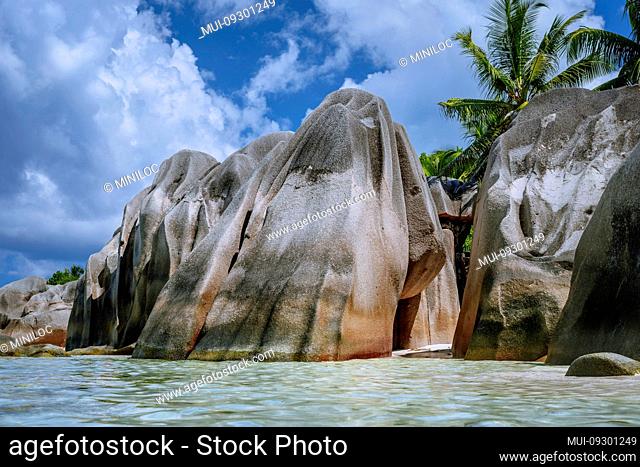 Anse Source d'Argent -Huge granite boulders between pal trees on tropical sandy beach against blue sky with white clouds. La Digue Island, Seychelles