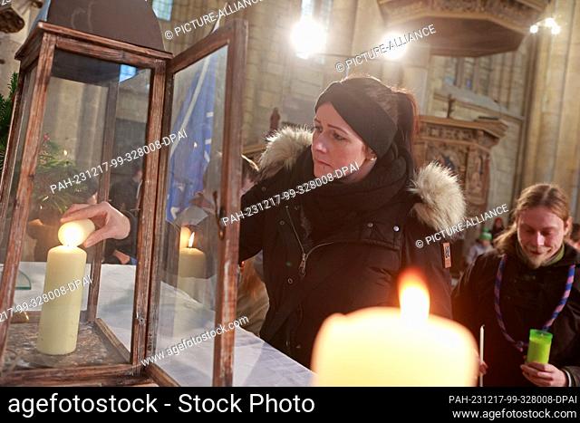 17 December 2023, Saxony-Anhalt, Halberstadt: Participants in an ecumenical service receive the Light of Peace from Bethlehem in St. Sixtus and St
