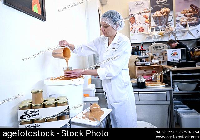 PRODUCTION - 12 December 2023, Berlin: Employee and Head of Marketing Janine Judetzki fills almond paste into jars in the store of Neukölln-based marzipan...