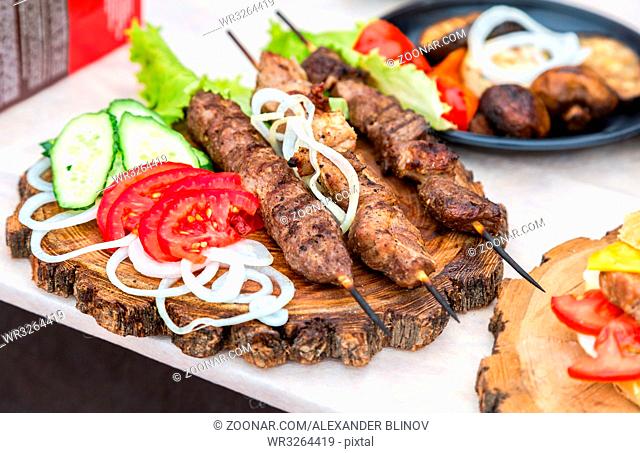 Grilled shish kebab or shashlik on wooden skewers with fresh vegetables