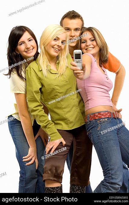 Three young woman and a man. Woman on the right is holding mobile phone and showing its screen to the camera. Isolated on white in studio