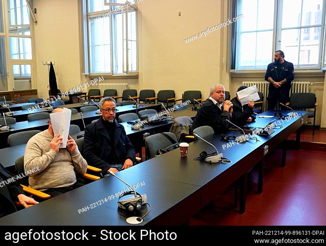 14 December 2022, Hamburg: The defendants sit in the courtroom in the Criminal Justice Building and hold pieces of paper in front of their faces