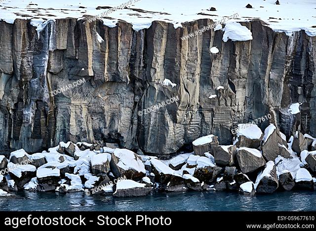 Steep frozen rocky river shore in Iceland. Closeup. Horizontal