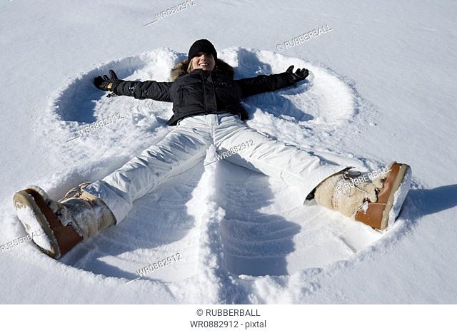 High angle view of a young woman lying in snow making a snow angel