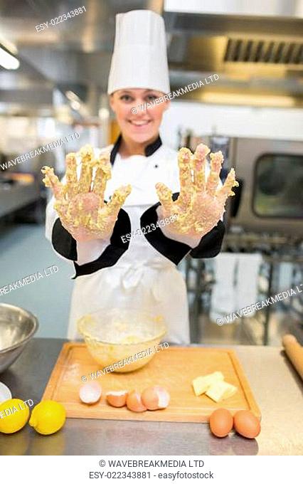 Baker showing her hands with dough while smiling