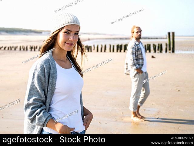Smiling young woman with man at beach during sunny day