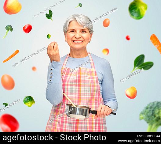 senior woman in apron with pot cooking food