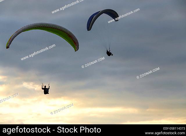 A paraglider soars in the sky at sunset